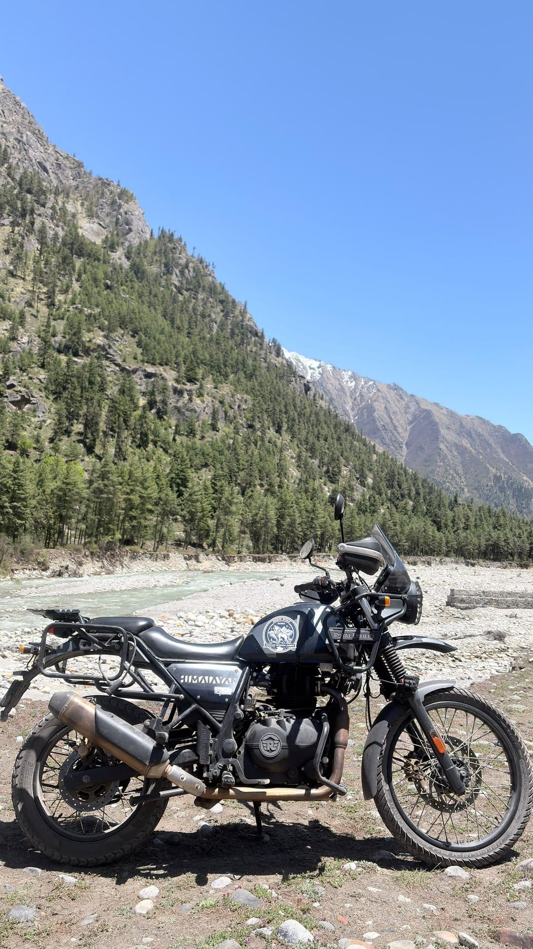 A Royal Enfield Himalayan parked beside a glacial river